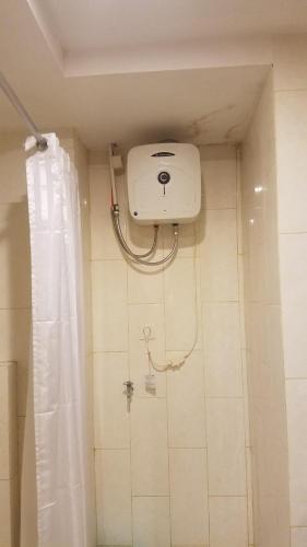 een douche in een badkamer met een wit douchegordijn bij Lavenderbnb Room 10 at Mataram City Apartment in Yogyakarta