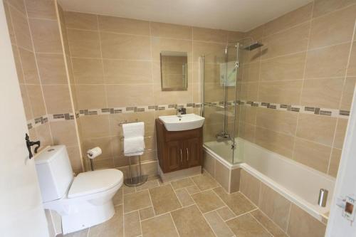 La salle de bains est pourvue de toilettes, d'un lavabo et d'une douche. dans l'établissement The Woodhouse Arms, à Grantham