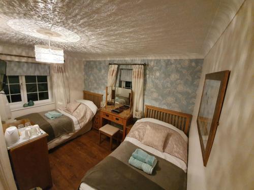 a bedroom with two beds and a desk and a mirror at Craig Eithin B & B in Holyhead