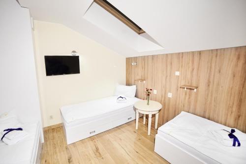 a white room with two beds and a table at Ośrodek Ukazia in Orzechowo