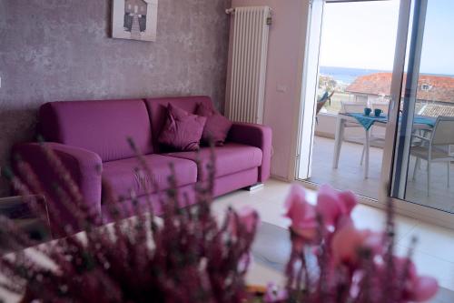 a living room with a purple couch and a balcony at Residence Millecento in Cesenatico