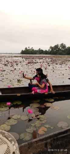 two girls sitting on a dock in a field of flowers at Aqualillies Water Front Heritage Homestay in Kumarakom