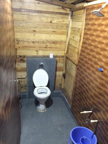 a bathroom with a toilet with a wooden wall at Blue Corner Beach Huts & Restaurant in Benaulim