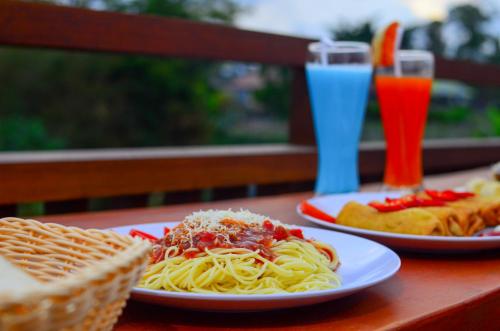 two plates of pasta on a table with drinks at Villa Danu Kintamani in Kintamani