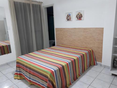 a bed with a colorful blanket on it in a room at Astúrias Guarujá in Guarujá