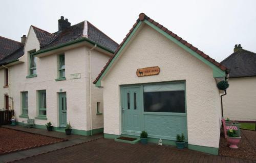 a white house with a green garage at taigh beag in Fort William