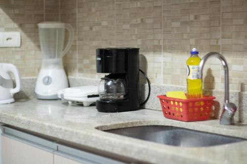a kitchen counter with a sink and a coffee maker at Flat Bantu - Aconchegante Flat no coração de Porto de Galinhas - Aqui seu pet é bem vindo in Porto De Galinhas