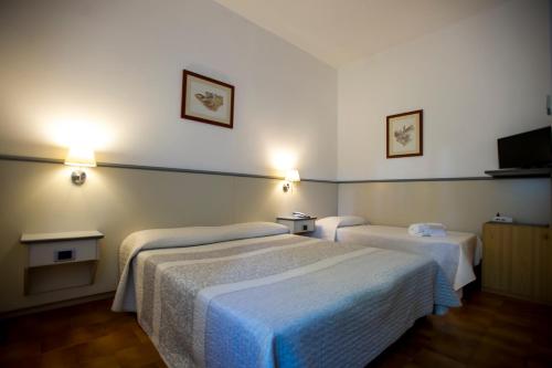 a hotel room with two beds and lights on the wall at Hotel Ai Tufi in Siena