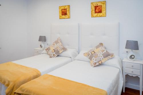 two beds in a room with white walls at Apartamento El Gigante in Ronda