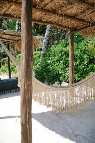 a hammock in a straw hut with bushes at NEST Tulum in Tulum
