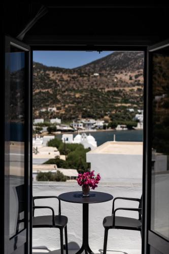 a table with a vase of flowers on a balcony at SifnosLiving A1 in Vathi