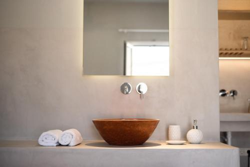 a bathroom with a wooden bowl on a counter with towels at SifnosLiving A1 in Vathi