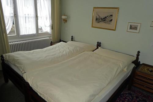 a bedroom with a large bed with white sheets at Villa Deck in Brunnen