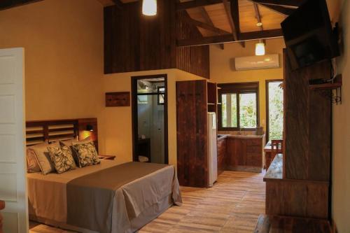 ein Schlafzimmer mit einem Bett und einem TV sowie eine Küche in der Unterkunft Complexo de Pousadas Caraguatá in Ilha do Mel