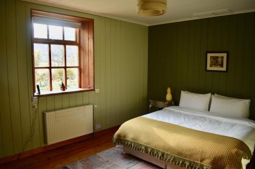 Dormitorio verde con cama y ventana en Stable Cottage, CrannachCottages, en Garve