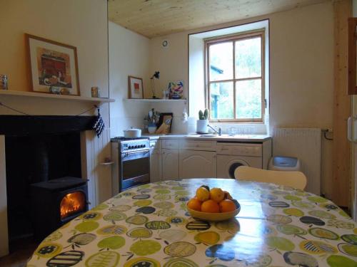 una cocina con una mesa con un bol de fruta. en Stable Cottage, CrannachCottages, en Garve