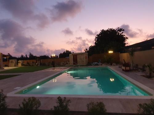 a swimming pool in a backyard at sunset at Villa Yioukkas in Paphos City