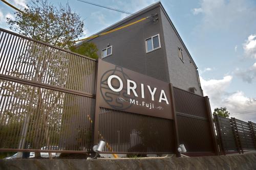 a building with a sign on the side of a fence at 21 ORIYA Mt Fuji -縁ENISHI- in Fujikawaguchiko