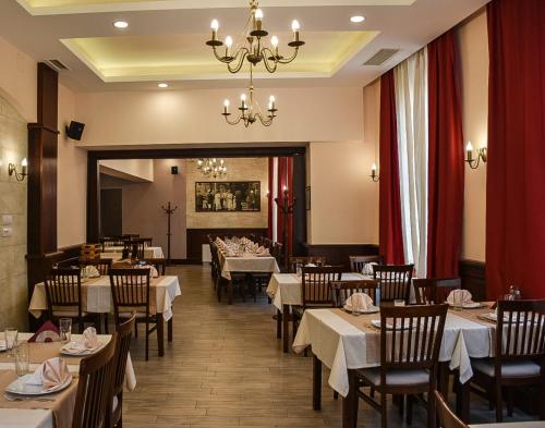 a restaurant with tables and chairs and a chandelier at Stari Slon in Sombor