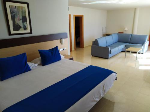 a bedroom with a large bed and a blue couch at Hotel Pocillos Playa, solo Adultos in Puerto del Carmen