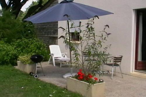um pátio com um guarda-sol e cadeiras azuis e um grelhador em Gite rural Herbignac - La Roche Bernard em Herbignac