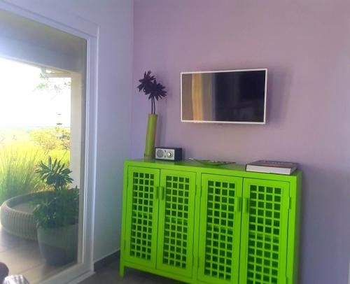 a green cabinet in a room with a tv on a wall at Finca Colibri in Boca Chica