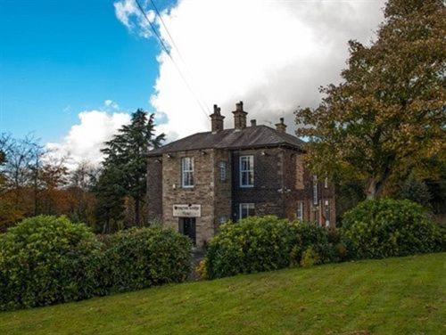 an old brick house with bushes in front of it at Gomersal Lodge Hotel in Cleckheaton