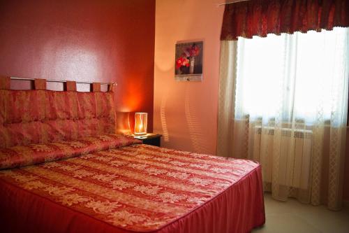 a bedroom with a bed with a red bedspread and a window at Bono Vacanze Villa San Marco Luxury Holidays Homes in Sciacca