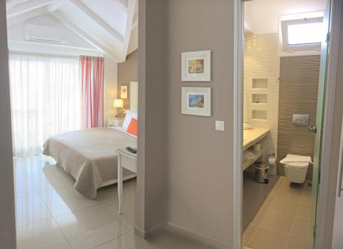 a bedroom with a bed and a bathroom with a sink at Haris Hotel Apartments and Suites in Paralia Vrachou