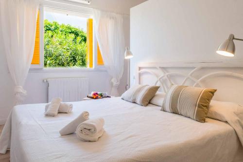 1 dormitorio con 1 cama blanca grande y toallas. en Villa Vica, en Santanyí
