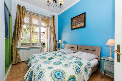 a blue bedroom with a bed and a window at Parkowa Maison de Sophie moj-sopot pl in Sopot