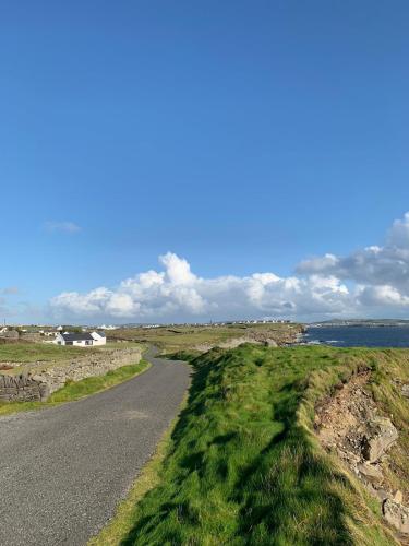 an empty road in the middle of a field at Spectacular ocean views & minutes to Cliffs- Clahane Shore Lodge in Liscannor