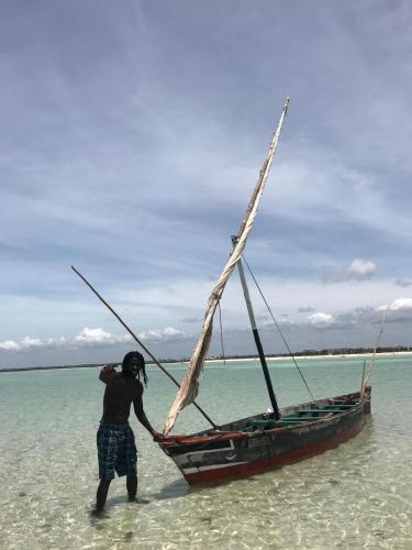 a man is standing in the water next to a boat at BeB Sardegna2 Anjumasa village in Watamu
