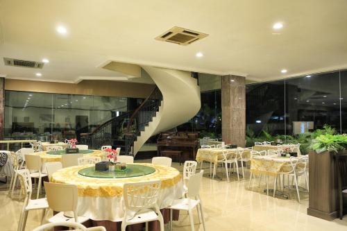a restaurant with tables and chairs and a spiral staircase at Hotel 55 in Jakarta