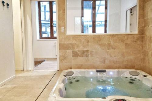 eine Whirlpool-Badewanne in einem Zimmer mit Fenster in der Unterkunft Maison cosy complètement rénovée in Gertwiller