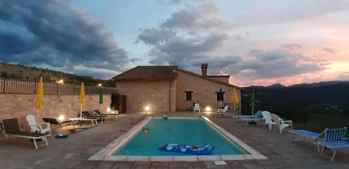 una villa con piscina di fronte a un edificio di Agriturismo I CASALI DI MORRO a Sellano