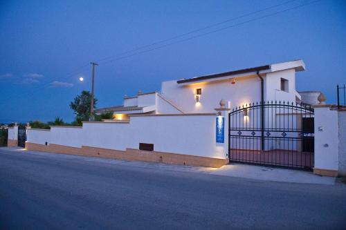 a white house with a gate at night at Bono Vacanze Villa San Marco Luxury Holidays Homes in Sciacca