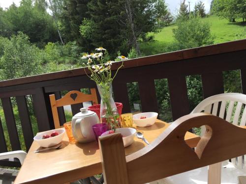 une table en bois avec un vase de fleurs sur le balcon dans l'établissement Coeur des Alpes, à Combloux