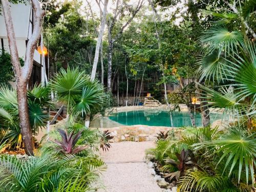 a swimming pool in a garden with palm trees at Nahouse Jungle Lodges in Tulum