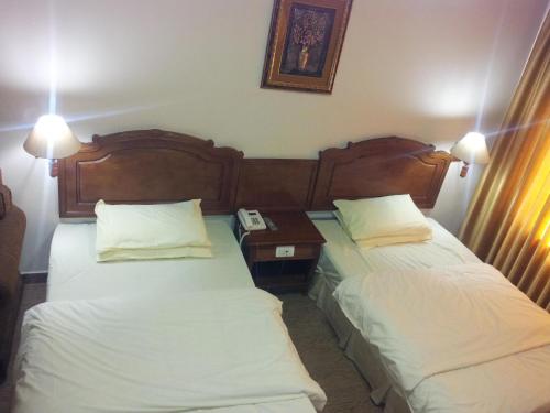 a hotel room with two beds and a table with a phone at Rana Palace in Amman