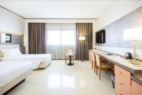 a hotel room with two beds and a desk at Best Western Modena District in Campogalliano