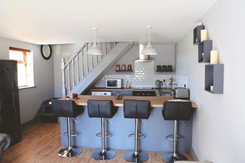 a kitchen with a counter with stools and a staircase at Dolmen Cottage in Glencolumbkille