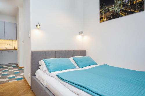 een bed met blauwe kussens in een kamer bij Apartments Warsaw Franciszkańska in Warschau