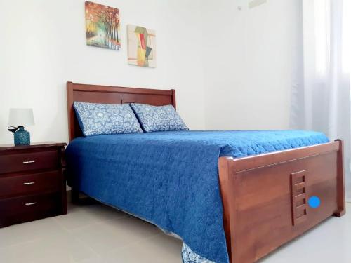 a bedroom with a bed with a blue bedspread and a nightstand at Paraiso de verano in Santiago de los Caballeros