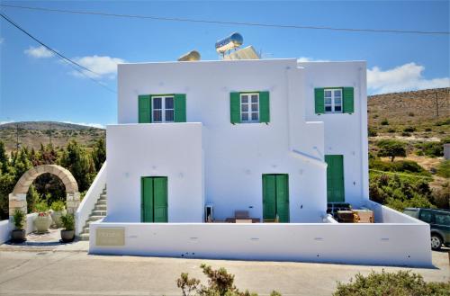 une maison blanche avec des portes vertes sur une colline dans l'établissement Dioni lux inn, à Pachaina
