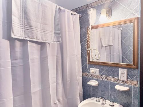 a bathroom with a white shower curtain and a sink at Hotel Cumbres Nevadas in El Chalten