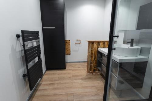 a bathroom with a white sink and a black door at La Dimiere - Le Postel - Appartements de standing en hyper-centre - Louviers in Louviers