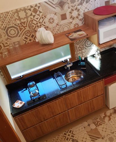 a kitchen counter with a sink and a microwave at Robinson Cottage Monte Verde MG in Monte Verde
