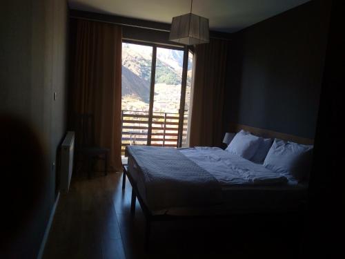 a bedroom with a bed and a large window at Hilltop Kazbegi in Stepantsminda
