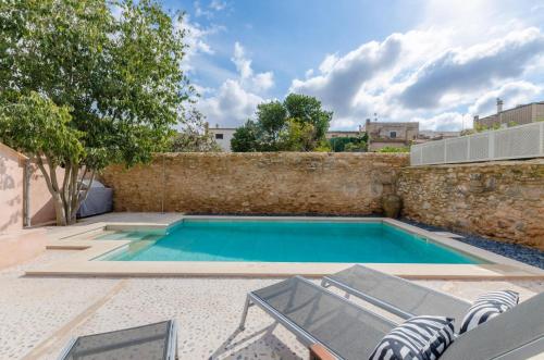 a swimming pool with chairs and a stone wall at Jaume II in Llucmajor